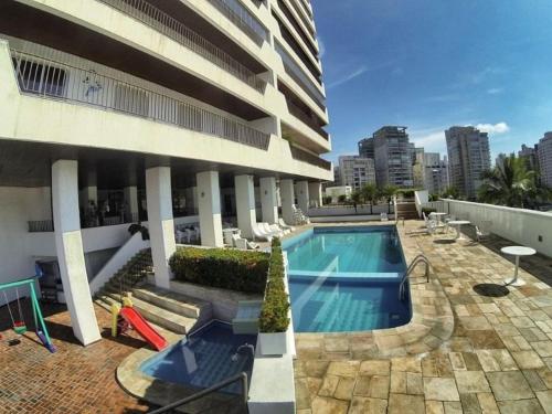 um edifício com piscina ao lado de um edifício em Condomínio Costa Esmeralda no Guarujá