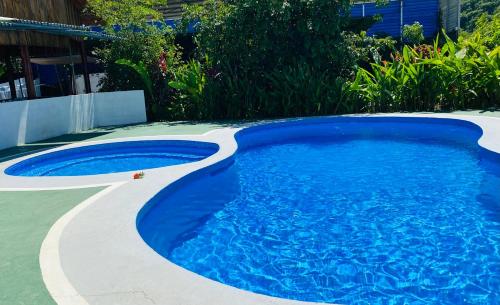 a swimming pool with blue water in a yard at HOTEL QUEPOS PARAISO i in Quepos