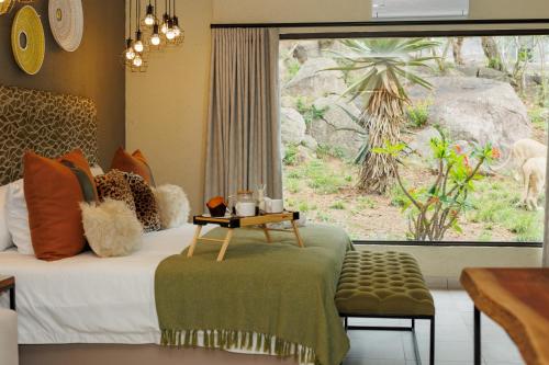 a bedroom with a bed with a table and a window at Pumbaa Wildlife Park & Accommodation in Nelspruit