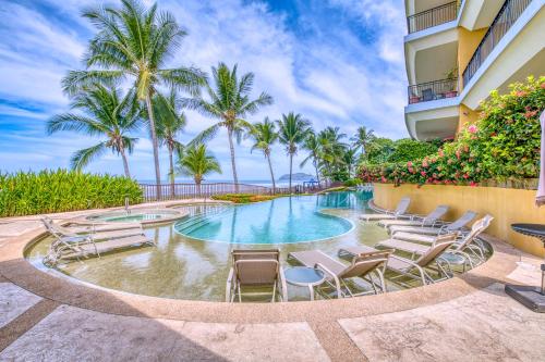 una piscina con tumbonas y palmeras en SecretJaco - Luxury Beach Front Penthouse with Pool & Jacuzzi, en Jacó