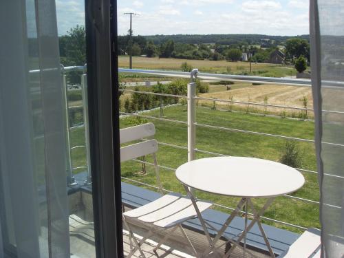 a white table and chair on a balcony with a view of a field at Chambre d'hôtes Les Bruyères in Bruc-sur-Aff