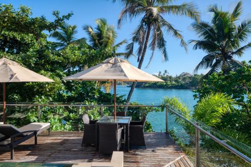 a wooden deck with tables and umbrellas overlooking a river at Beacon By The Bay Villas and Suites by the Clarks in Matara