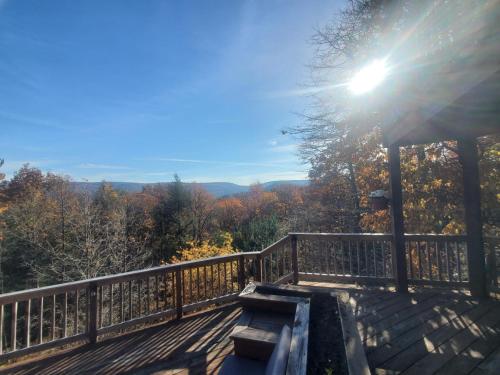a wooden bench on a deck with the sun shining at Mountain house in Palmerton