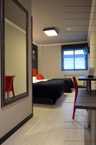 a bedroom with a bed and a mirror and a table at HOTEL CEAO in Lugo