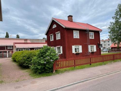 a red house with a fence on the side of a street at MoraTelegrafen in central Mora in Mora
