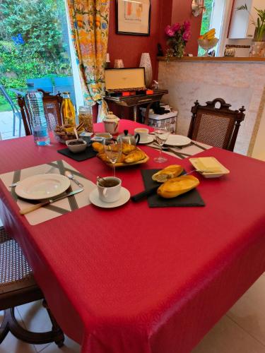 a table with a red table cloth with plates and glasses at L'Orée in Verneuil-en-Halatte
