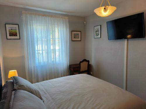 um quarto com uma cama e uma televisão de ecrã plano em L'Orée em Verneuil-en-Halatte