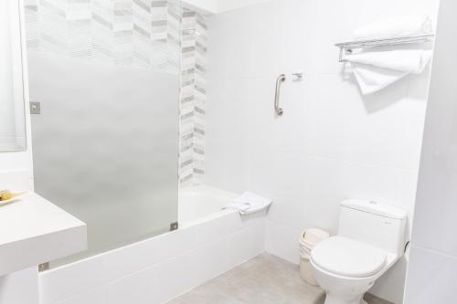 a white bathroom with a toilet and a bath tub at Hotel San Blas in Lima