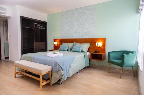 um quarto com uma cama e uma cadeira verde em Hotel San Blas em Lima