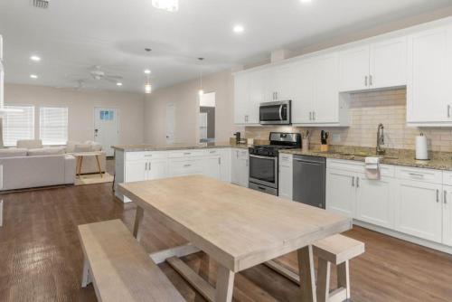 a large kitchen with white cabinets and a wooden table at The Gator Grove Retreat in Gainesville