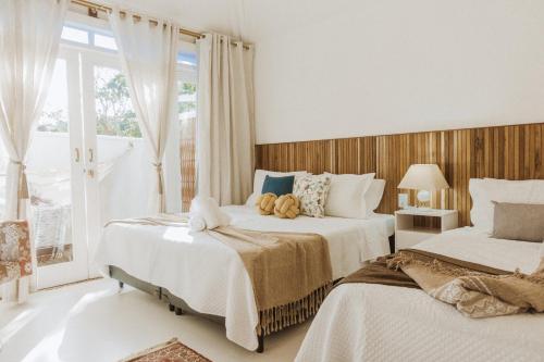 Un dormitorio con dos camas y una ventana. en Casa Blanca Conforto Neoclásico, Búzios/RJ, en Búzios