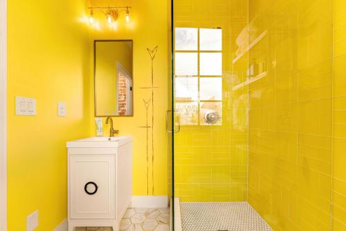 a yellow bathroom with a shower and a sink at The Acoma House in Denver