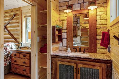 ein Blockhausbad mit einem Waschbecken und einem Spiegel in der Unterkunft Secluded & Charming Lake Access Woodland Chalet by Sarah Bernard in Innsbrook