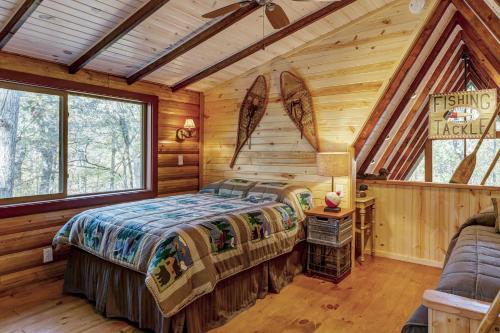 ein Schlafzimmer mit einem Bett in einem Blockhaus in der Unterkunft Secluded & Charming Lake Access Woodland Chalet by Sarah Bernard in Innsbrook
