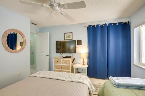 a bedroom with blue curtains and a tv at Beachfront St Augustine Condo with Pool Access in Saint Augustine