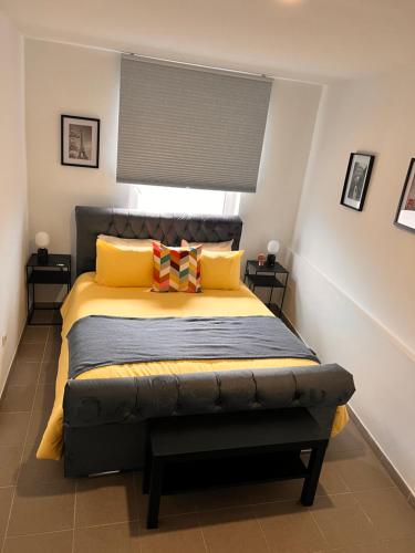 ein Schlafzimmer mit einem Bett mit gelben und orangefarbenen Kissen in der Unterkunft Résidence du moulin 2 B 2 in Boussu