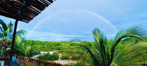 a rainbow in the sky over a beach with palm trees at Casa Celeste in Atins