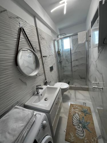 a bathroom with a sink and a shower with a mirror at Patrick apartament in Techirghiol