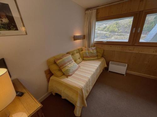 Cette petite chambre comprend un canapé et une fenêtre. dans l'établissement Studio cosy 2 pers, skis aux pieds, Les Menuires, quartier Brelin - FR-1-452-282, aux Menuires