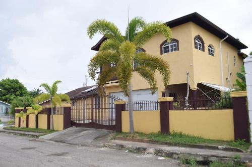 una casa amarilla con una palmera delante de ella en Rhyne Park Inn, en Montego Bay