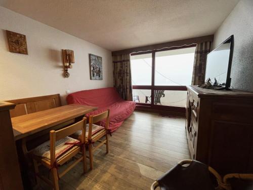 un salon avec une table et un canapé rouge dans l'établissement Studio duplex 4 personnes avec balcon, Brelin, Les Menuires - FR-1-452-151, aux Menuires