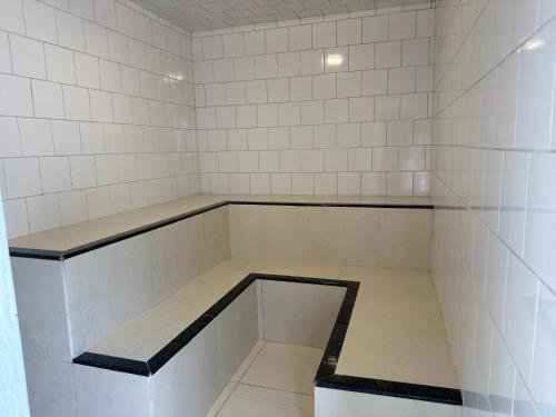 a empty room with white tiled walls and benches at POUSADA MINEIRA in Águas de São Pedro