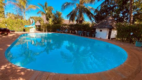 a large pool with blue water in a yard at Villas Dora and Holly in Diani Beach