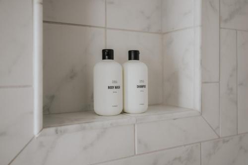 two white bottles sitting on a shelf in a bathroom at Rose carriage House Savannah in Savannah