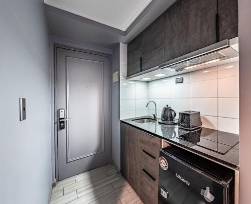 a kitchen with a stove and a sink and a door at Encomenderos Design Tech Comfort & Location in Santiago