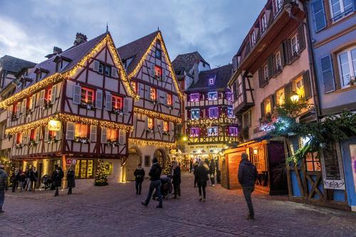 Un gruppo di persone che camminano per strada con le luci di Natale di Les VENDANGEURS a Niedermorschwihr