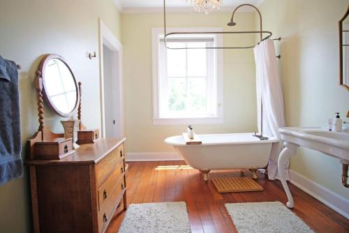a bathroom with a tub and a sink and a mirror at Hamilton House - 5BR Historic Home with Courtyard and Garage in Savannah