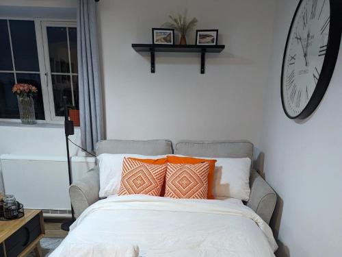 a bed with pillows and a clock on the wall at Bryngwalia Fach in Cribyn