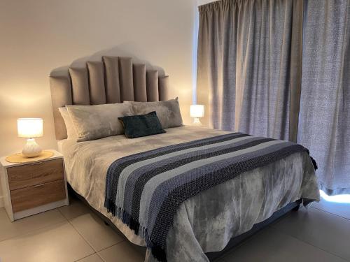a bedroom with a large bed with a large headboard at Ultra Modern Apartment - Self Catering in Ballito
