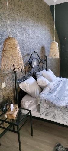 a bedroom with a bed and a table with a lamp at La folie 20 Spa in Hon-Hergies