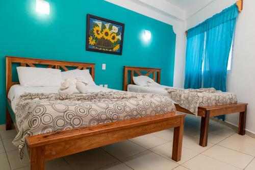 1 dormitorio con 2 camas y pared azul en Hotel Laurel Cancún Centro en Cancún