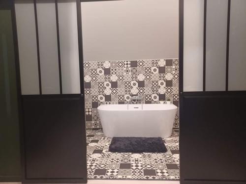 a bathroom with a tub and a tiled floor at La folie 20 Spa in Hon-Hergies