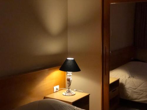 a lamp sitting on a table in a bedroom at Hotel Villa de Minas in Monte Sião