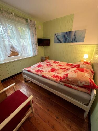 a bedroom with a bed with a red comforter and two windows at A&R Brzozowa 5 in Rowy