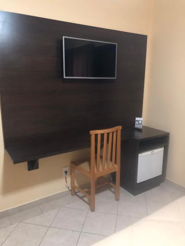 a chair in a room with a television on a wall at Hotel Villa de Minas in Monte Sião