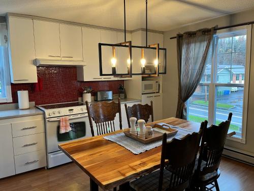 a kitchen and dining room with a wooden table at Floral'Anse in LʼAnse-Saint-Jean