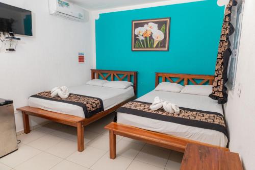 two beds in a room with a blue wall at Hotel Las Palmas en Laurel in Cancún