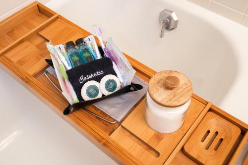 a wooden tray with toothbrushes and toiletries on a bath tub at Beard Avenue Bungalow! in Minneapolis