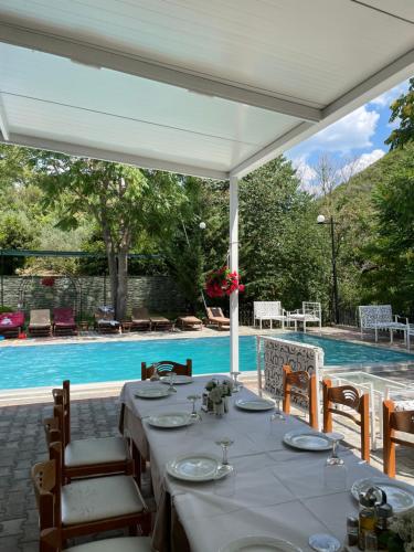 a table under a white canopy next to a swimming pool at Hotel Aroma in Përmet
