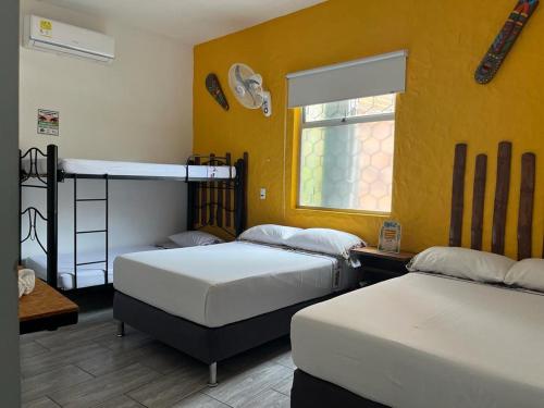 two beds in a room with yellow walls at HOTEL PH GIRARDOT in Girardot