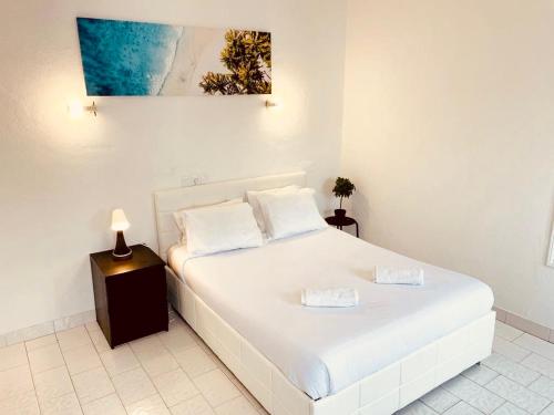 Un dormitorio con una cama blanca con una foto en la pared en Central Atlantic Beach Guesthouse, en Costa da Caparica