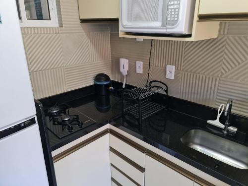 a small kitchen with a sink and a microwave at Fuja para o Paraíso em Porto de Galinhas! in Porto De Galinhas