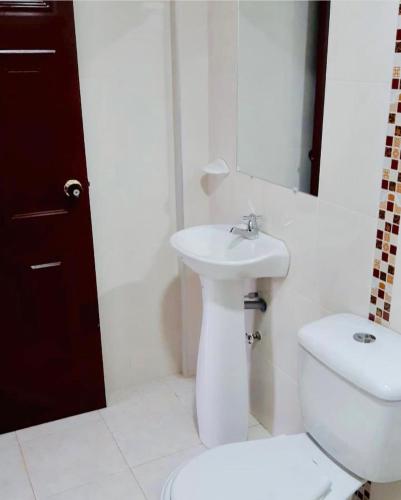 Un baño blanco con inodoro y lavabo. en Buen Vivir Restrepo a 30 minutos Lago Calima, en Restrepo