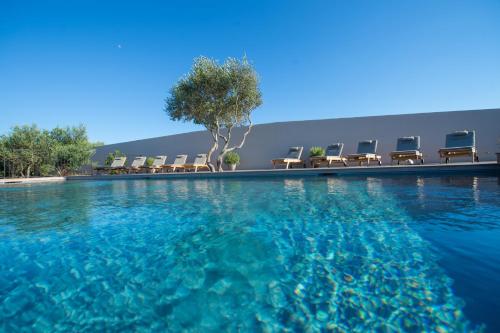 - une piscine avec des chaises et de l'eau bleue dans l'établissement Villa Madra, à Bonifacio