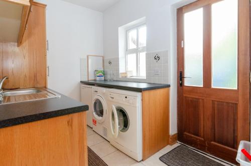 a kitchen with a washer and dryer next to a window at Rathmullan Village Home in Rathmullan
