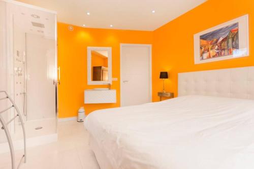 ein weißes Bett in einem Zimmer mit orangefarbenen Wänden in der Unterkunft L'Atelier 4 stars Luxury, Hot Tub, Pool in Nambsheim